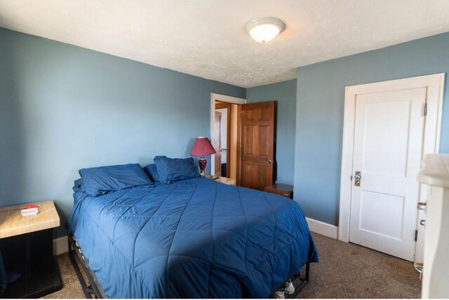 bedroom featuring a textured ceiling, baseboards, and carpet floors