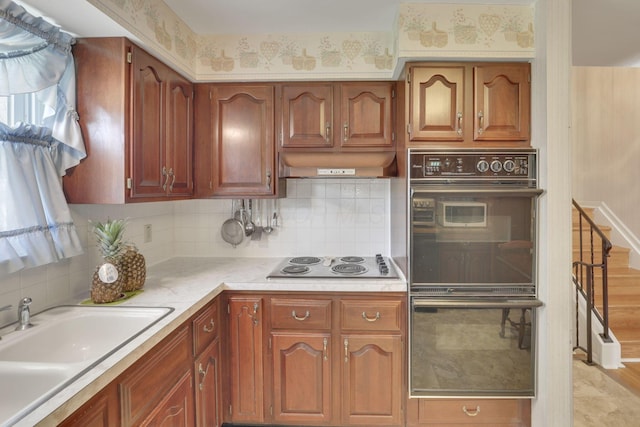 6693 Red Coach Ln, Reynoldsburg, OH 43068 - kitchen with electric cooktop, dobule oven black, a sink, light countertops, and under cabinet range hood