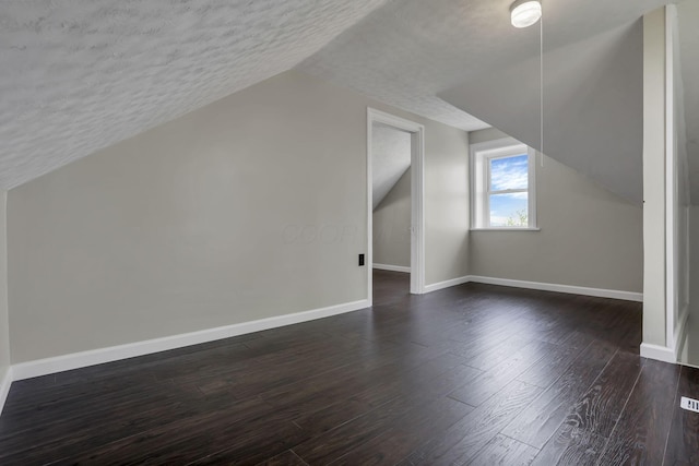 8400 16th Rd Unit Sw, Amanda, OH 43102 - bonus room with lofted ceiling, dark wood-style floors, visible vents, baseboards, and a textured ceiling
