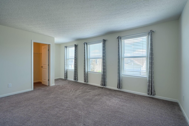 unfurnished room with a textured ceiling, baseboards, and carpet floors