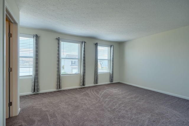 carpeted empty room with baseboards and a textured ceiling