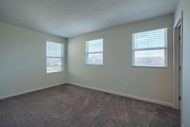 carpeted empty room with a textured ceiling and baseboards