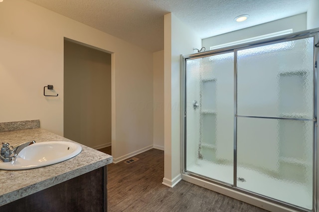 full bathroom with a stall shower, wood finished floors, baseboards, and visible vents