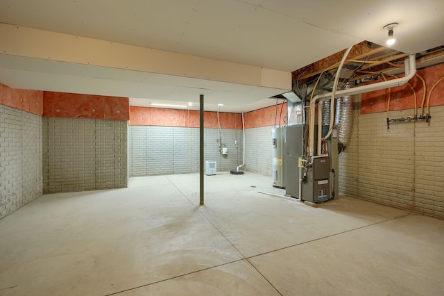 unfinished below grade area featuring brick wall, heating unit, and water heater