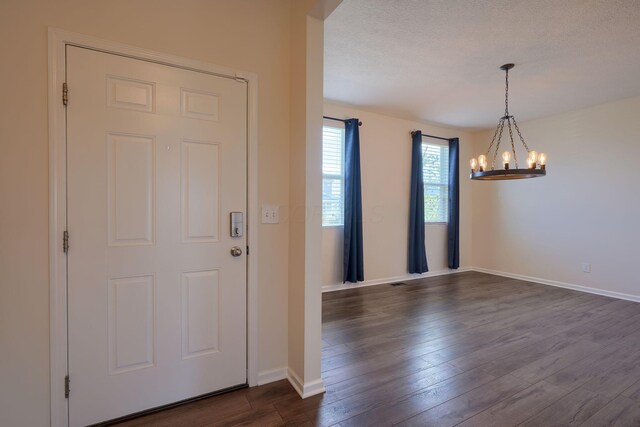 entryway featuring dark wood-style flooring, baseboards, and an inviting chandelier