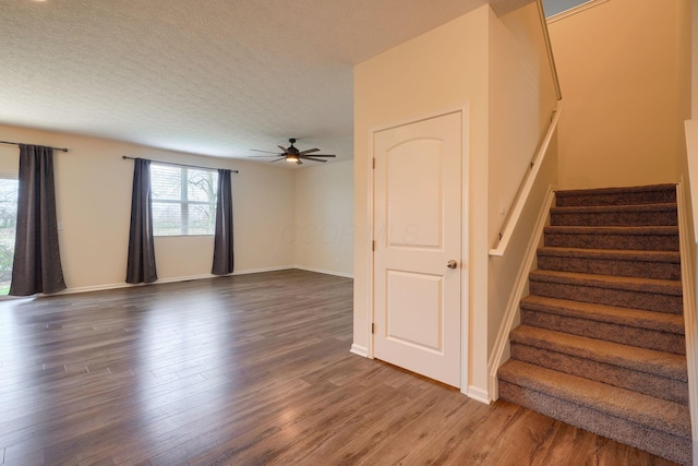 stairway with baseboards, a textured ceiling, wood finished floors, and ceiling fan