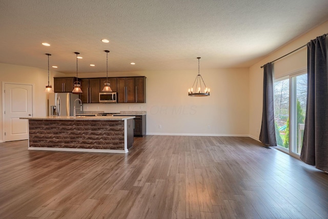 kitchen with a chandelier, dark wood-style floors, light countertops, dark brown cabinets, and appliances with stainless steel finishes