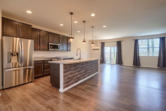 kitchen with a sink, appliances with stainless steel finishes, a kitchen island with sink, dark brown cabinetry, and recessed lighting