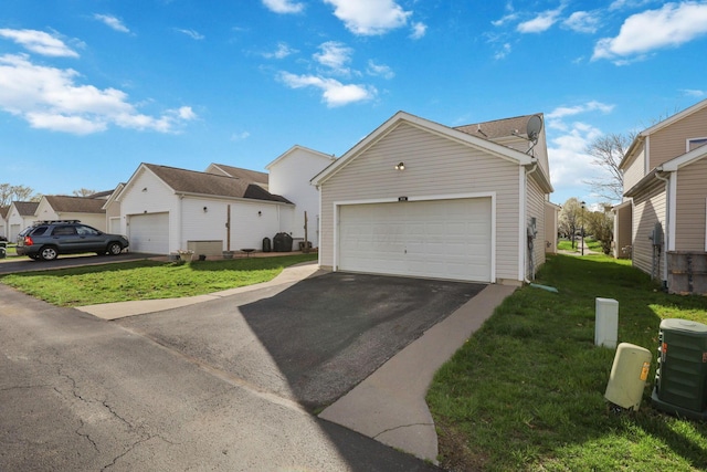 exterior space with a front lawn, an outdoor structure, a garage, and aphalt driveway