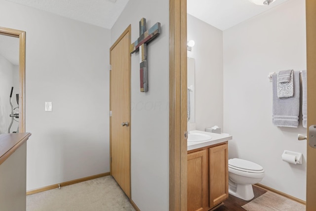 half bathroom featuring toilet, vanity, and baseboards