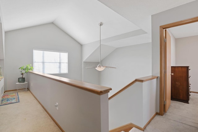 corridor with carpet flooring, an upstairs landing, baseboards, and lofted ceiling