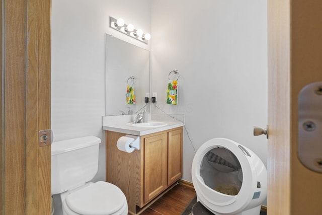 bathroom with toilet, vanity, and wood finished floors