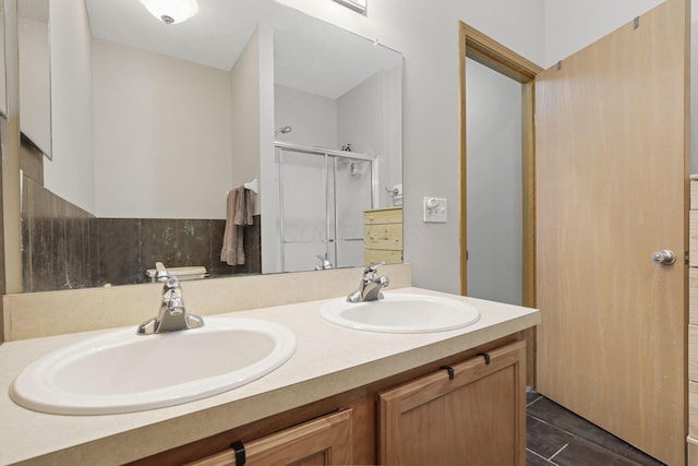 full bath with a stall shower, double vanity, and a sink