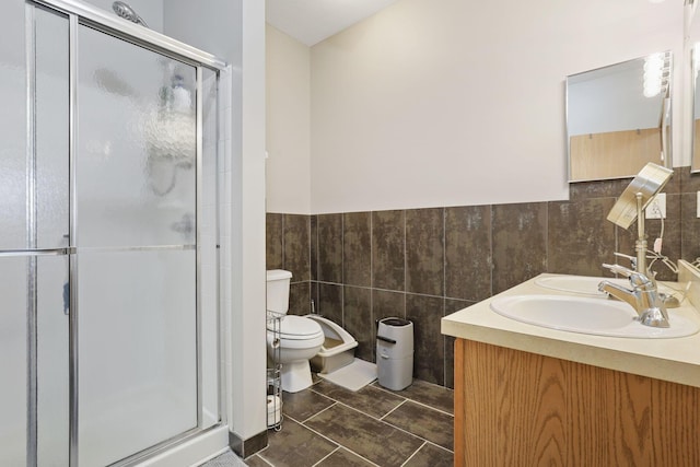full bath with a shower stall, toilet, a sink, and tile walls