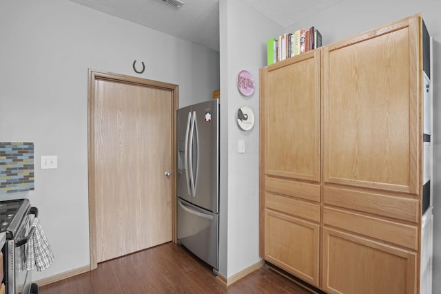 kitchen with stainless steel appliances, baseboards, light brown cabinetry, and dark wood finished floors