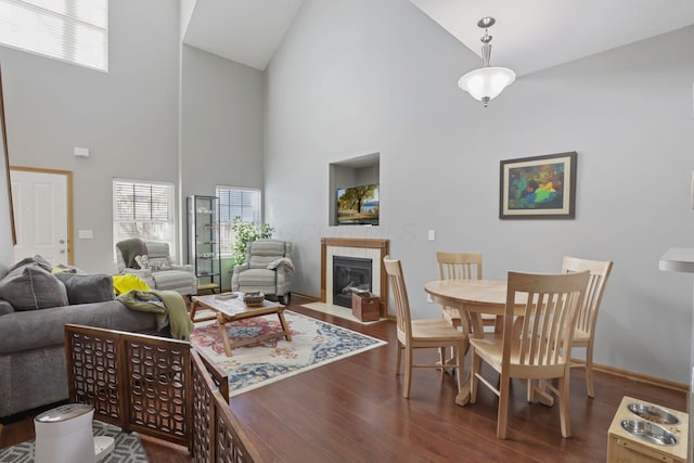 living room featuring a tile fireplace, wood finished floors, and high vaulted ceiling