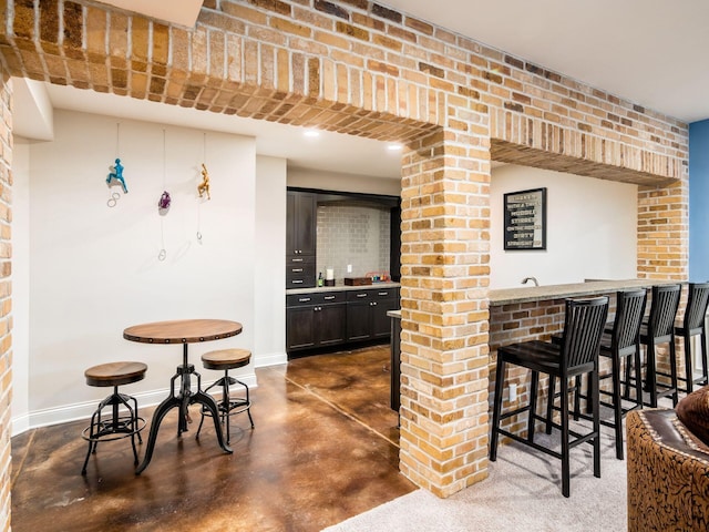 7251 Wilton Chase St, Dublin, OH 43017 - bar with baseboards, finished concrete floors, brick wall, and indoor wet bar