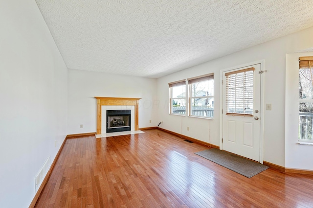 unfurnished living room with baseboards, hardwood / wood-style floors, a fireplace, and visible vents