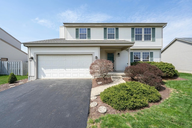 traditional-style home with driveway, a garage, and fence