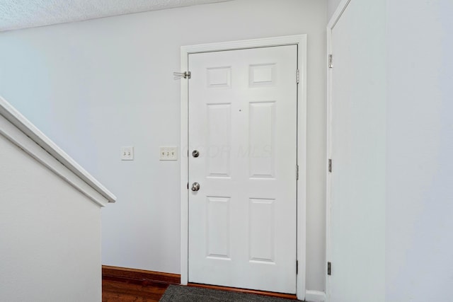 doorway with dark wood-type flooring and baseboards