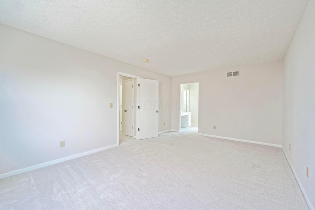 unfurnished room featuring light carpet, visible vents, baseboards, and a textured ceiling