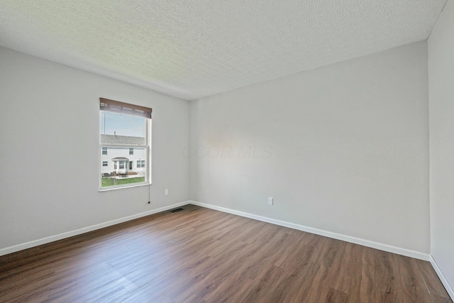 spare room featuring dark wood-style flooring, baseboards, and a textured ceiling