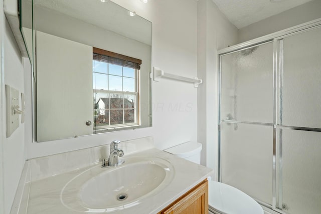 full bath with toilet, a shower stall, vanity, and a textured ceiling