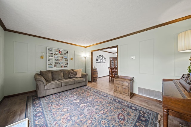 living room with crown molding, visible vents, wood finished floors, and a textured ceiling
