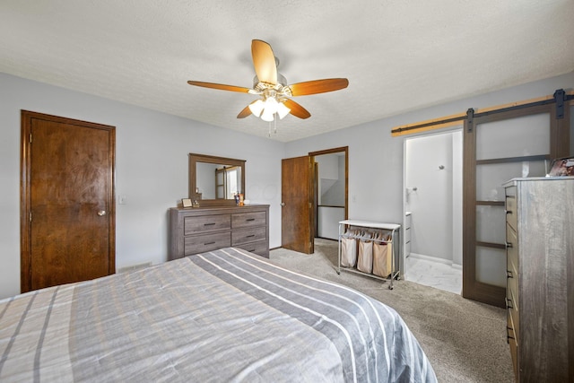 bedroom featuring carpet floors, a ceiling fan, a barn door, and a textured ceiling