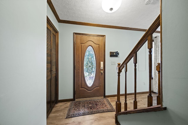 entrance foyer with crown molding, a textured ceiling, wood finished floors, stairs, and baseboards