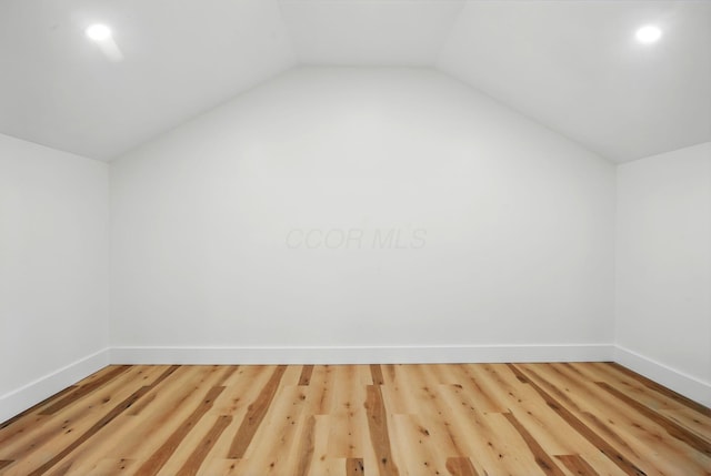 additional living space featuring baseboards, vaulted ceiling, and wood finished floors