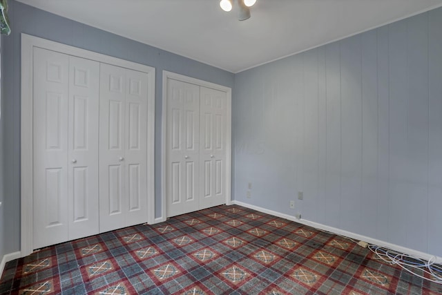 unfurnished bedroom with baseboards and two closets
