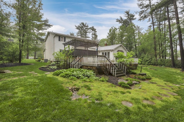 rear view of property with a lawn, a wooden deck, and stairs