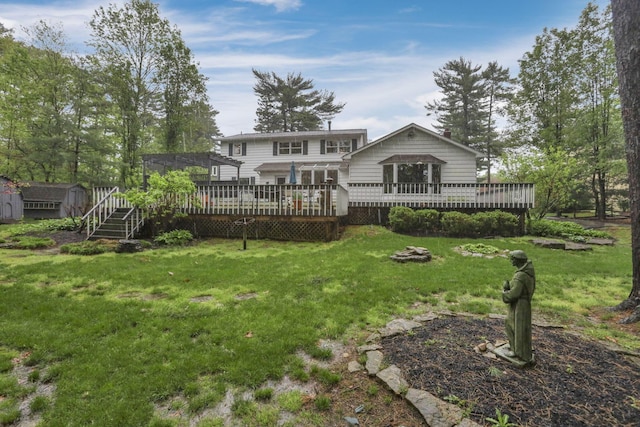 back of property featuring a lawn, a wooden deck, an outbuilding, and a shed
