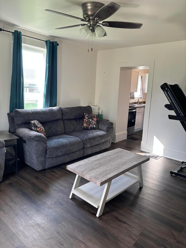 living area featuring dark wood-type flooring, baseboards, and a ceiling fan