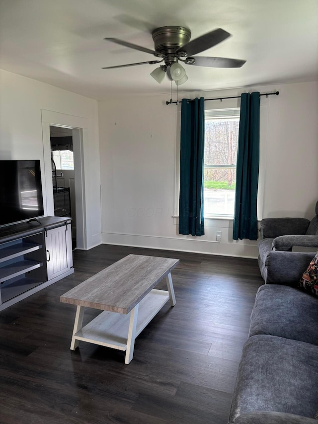 living room featuring baseboards, a ceiling fan, and dark wood-style floors