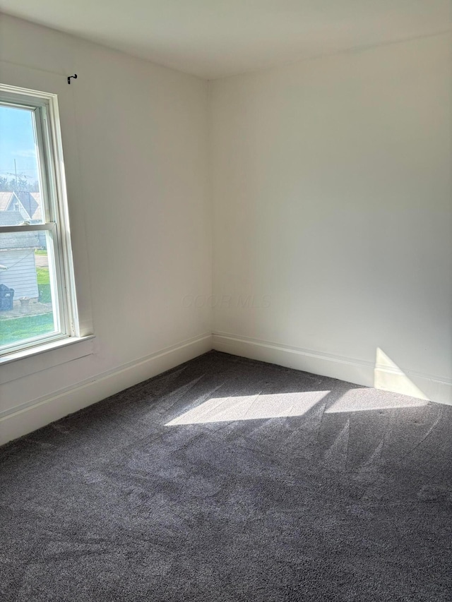 spare room featuring carpet flooring and baseboards