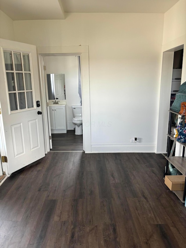 interior space featuring a sink, connected bathroom, and dark wood-style floors