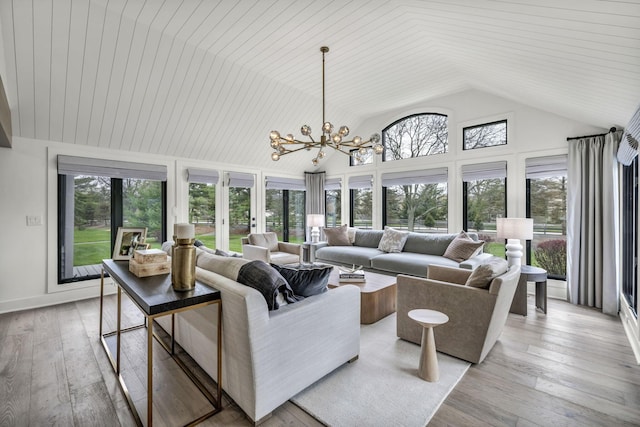 living room featuring high vaulted ceiling, an inviting chandelier, light wood-style floors, and plenty of natural light