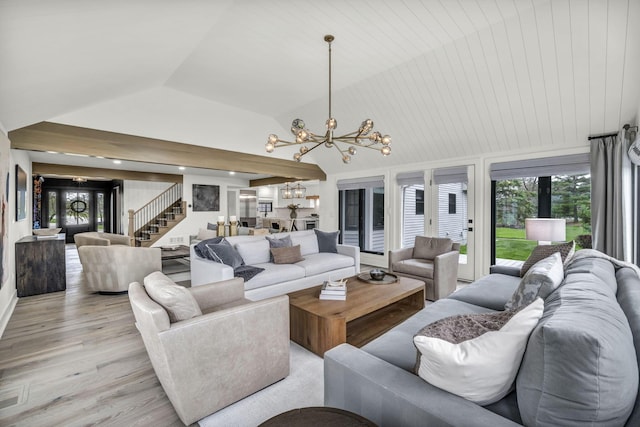 living area with stairway, an inviting chandelier, light wood-style floors, and lofted ceiling