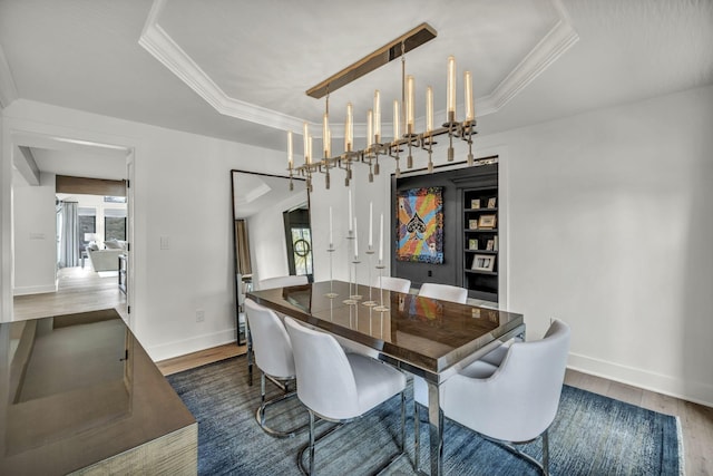 dining area with wood finished floors, a raised ceiling, crown molding, and baseboards