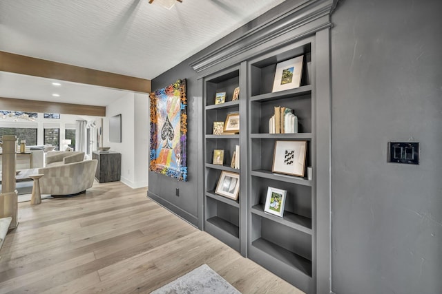 corridor with baseboards, light wood-type flooring, and built in features