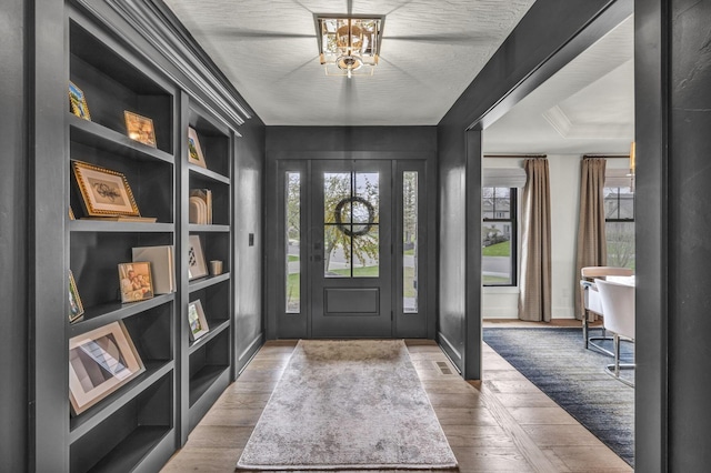 foyer entrance featuring an inviting chandelier, a wealth of natural light, and wood finished floors
