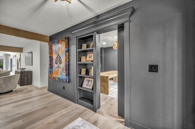 hall featuring wood finished floors, baseboards, and built in shelves