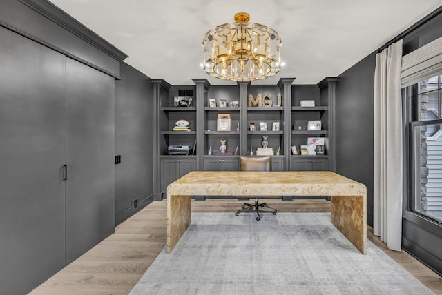 office space with an inviting chandelier, light wood-style floors, and built in features