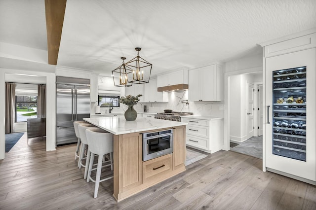 kitchen featuring light wood-style floors, wine cooler, a kitchen bar, built in refrigerator, and a kitchen island