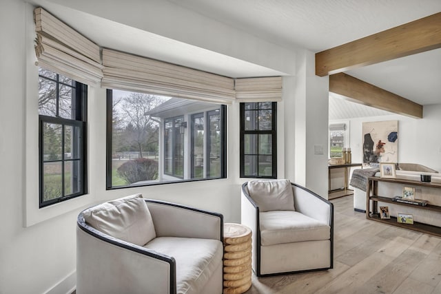 sitting room featuring baseboards, beamed ceiling, a wealth of natural light, and light wood-style flooring
