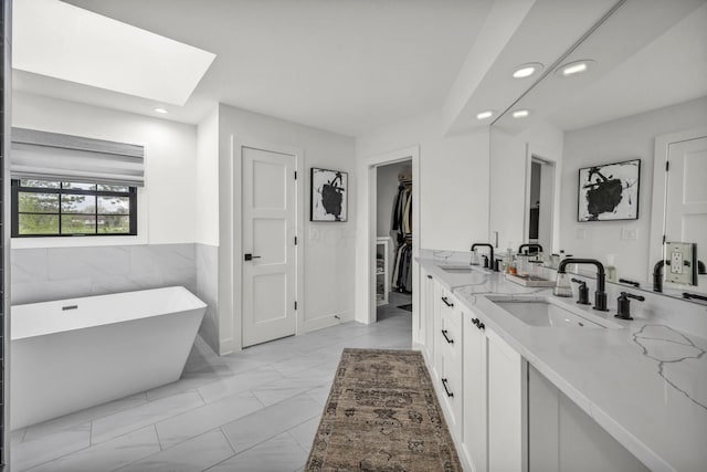 bathroom with recessed lighting, a skylight, and a sink