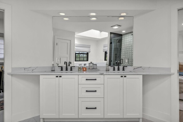 ensuite bathroom with double vanity, a sink, a shower stall, and connected bathroom