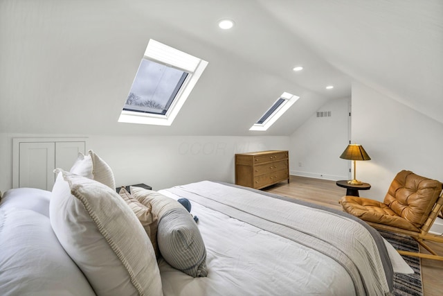 bedroom with light wood-style flooring, vaulted ceiling with skylight, visible vents, baseboards, and recessed lighting